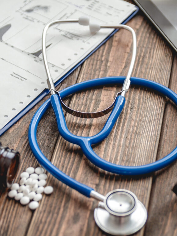 Medical card of patient, stethoscope, tablet on wooden table