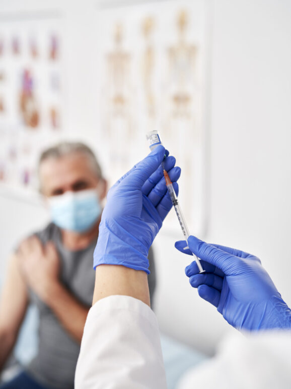 Vertical image of doctor preparing syringe for senior patient