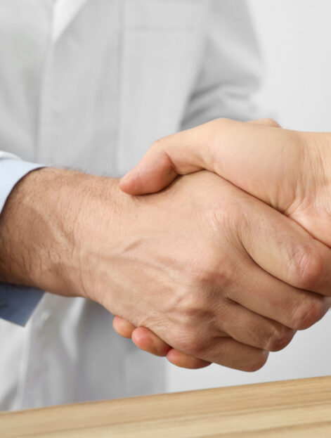 Doctor shaking hands with patient in hospital, closeup